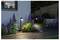 Moderne aangelegd tuin in de schemering met gloeiende padverlichting, paarse bloemen en een houten loopbrug naast een huis.