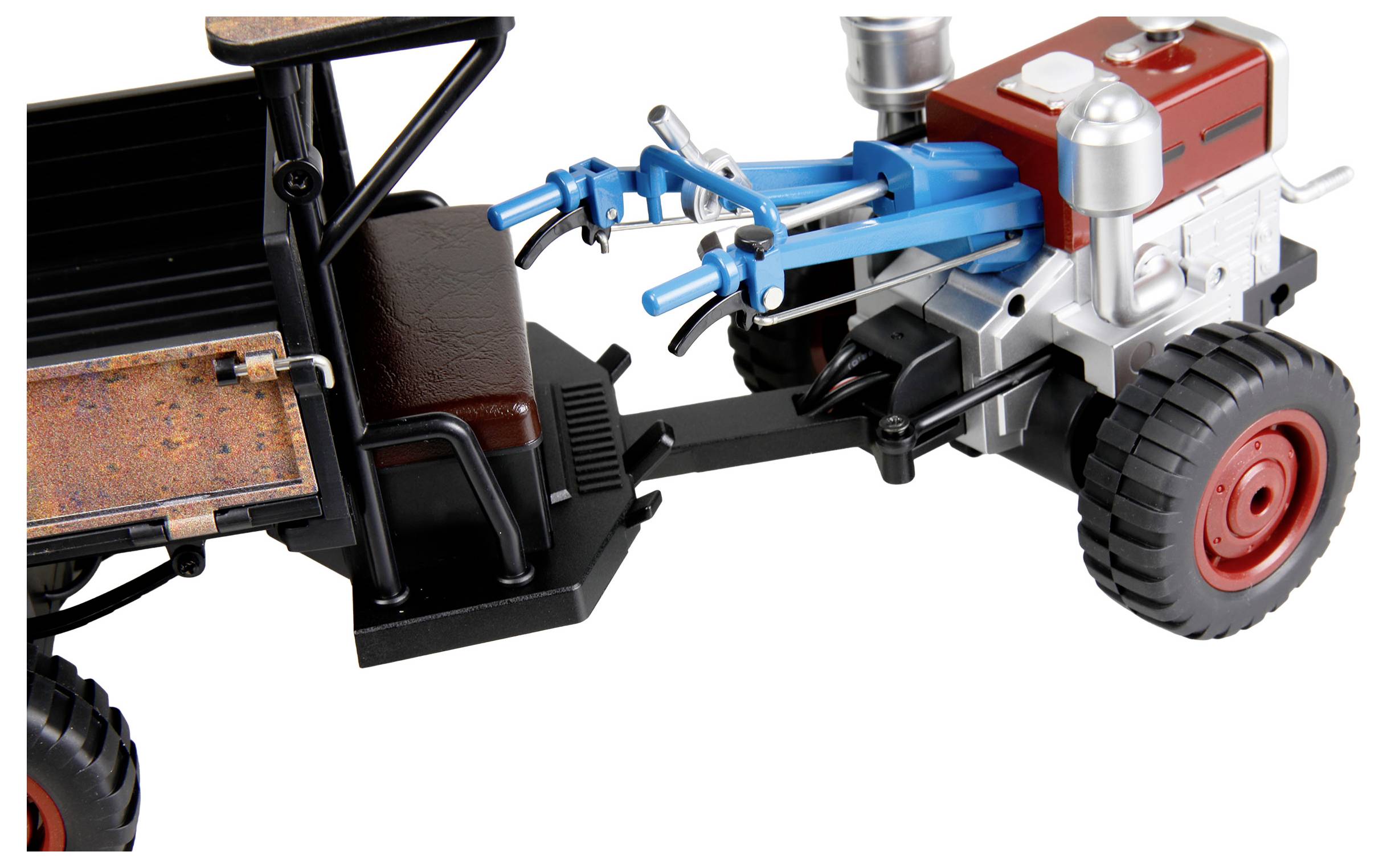 Een speelgoedtrekker-aanhanger of landbouwvoertuigmodel met een rood motorblok, zwarte cabine en een blauw fronttreinmechanisme op een witte achtergrond.