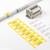 Kabel- en aansluitbloklabels op een wit oppervlak gerangschikt, met gele en witte identificatielabels voor draden en een aansluitblok met gelabelde sleuven.