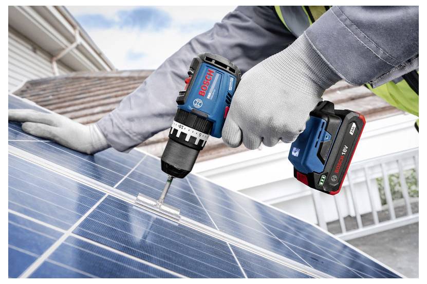 Werknemers met handschoenen die met een Bosch accuboormachine een bevestiger in zonnepanelen op het dak boren.