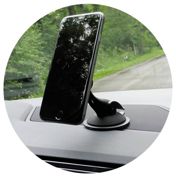 Smartphone gemonteerd in een autodashoboardhouder, schuin naar de bestuurder gericht, met een weg zichtbaar door de voorruit.