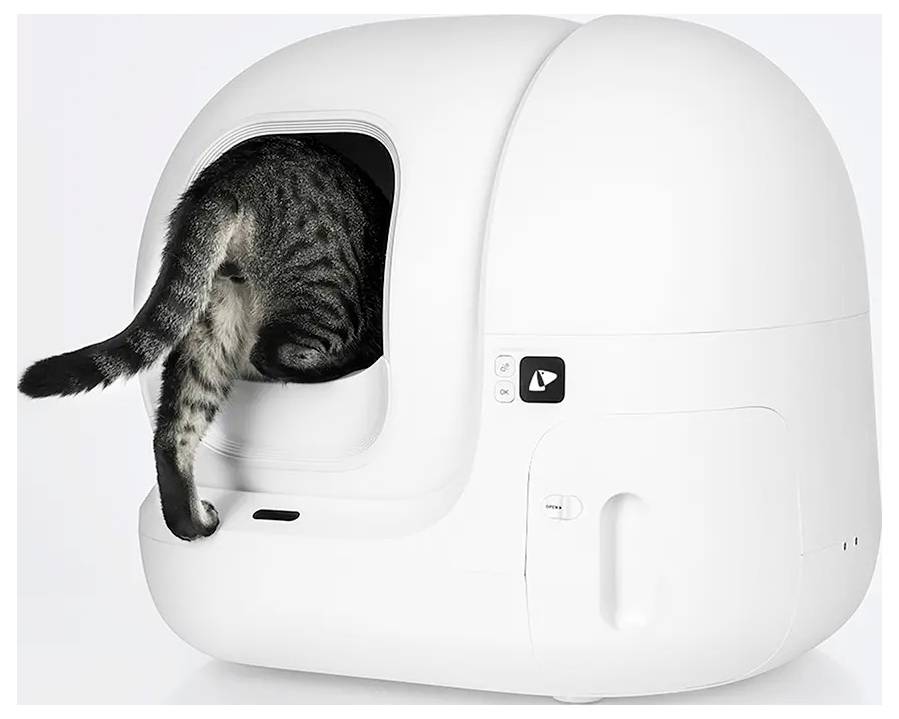 Kat die een witte gesloten zelf-reinigde kattenbak binnengaat, met zijn staart en achterpoten uitstekend uit de opening.