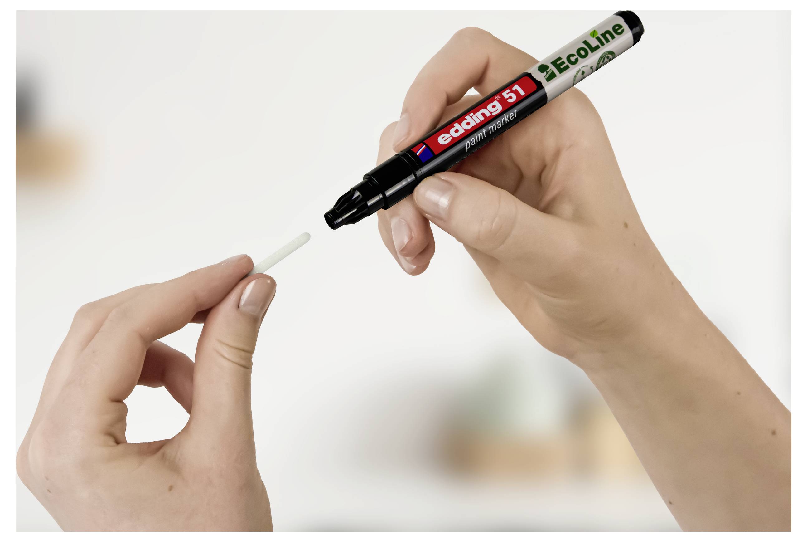 Handen houden een zwarte Edding Ecoline marker vast en het dop ervan, waarbij het dop van de penpunt wordt verwijderd.