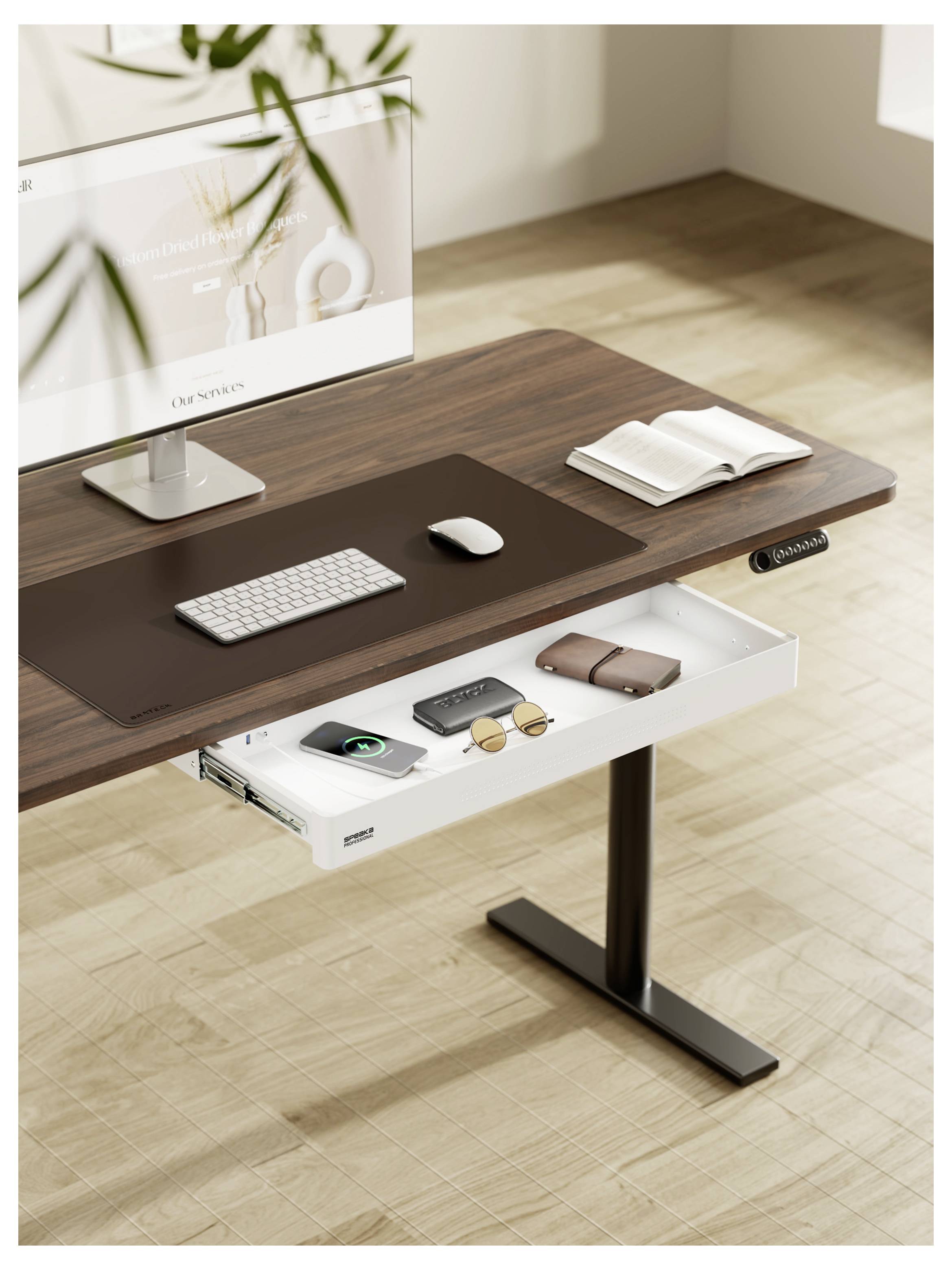 Modern stafelbureau met monitor, toetsenbord, muis, open notitieboek en een uitschuifbare lade met accessoires op een licht houten vloer.