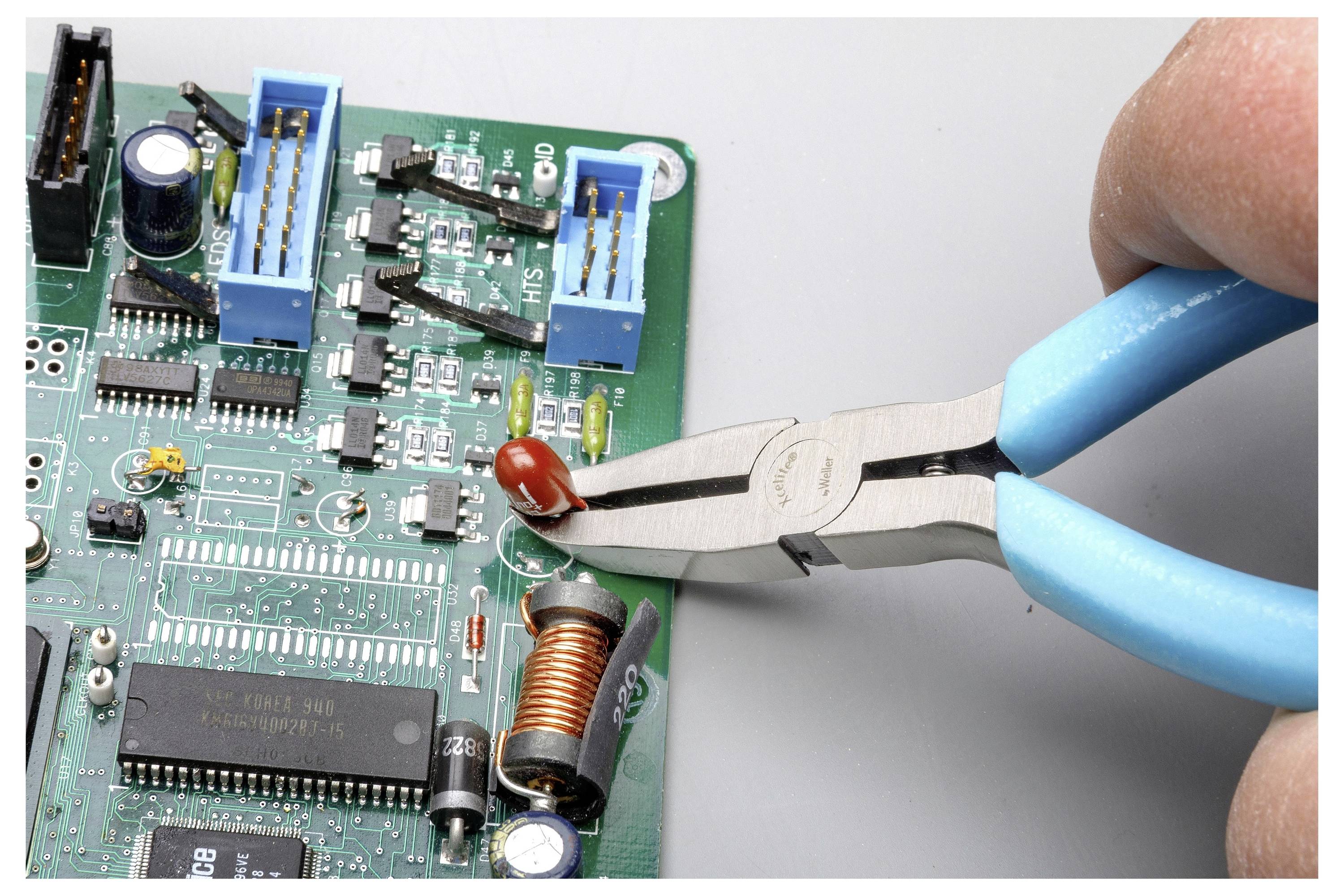 Blauw-handvat tang verwijdert een rood onderdeel van een printplaat tijdens elektronica-reparatie.