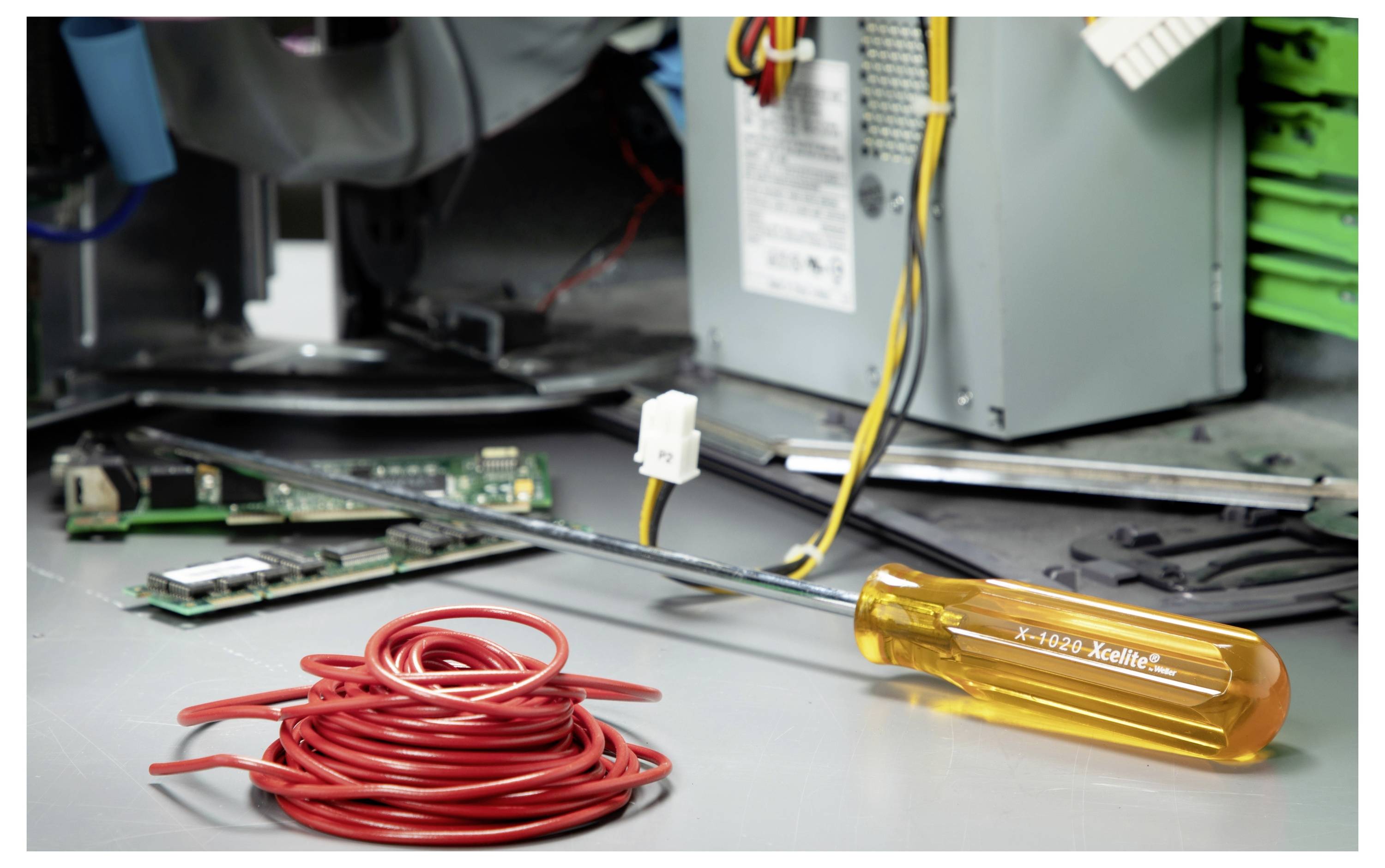 Open computerbehuizing met rode kabelspoel en oranje schroevendraaier op het metalen chassis, wat suggereert dat er PC-reparatie of montage plaatsvindt.