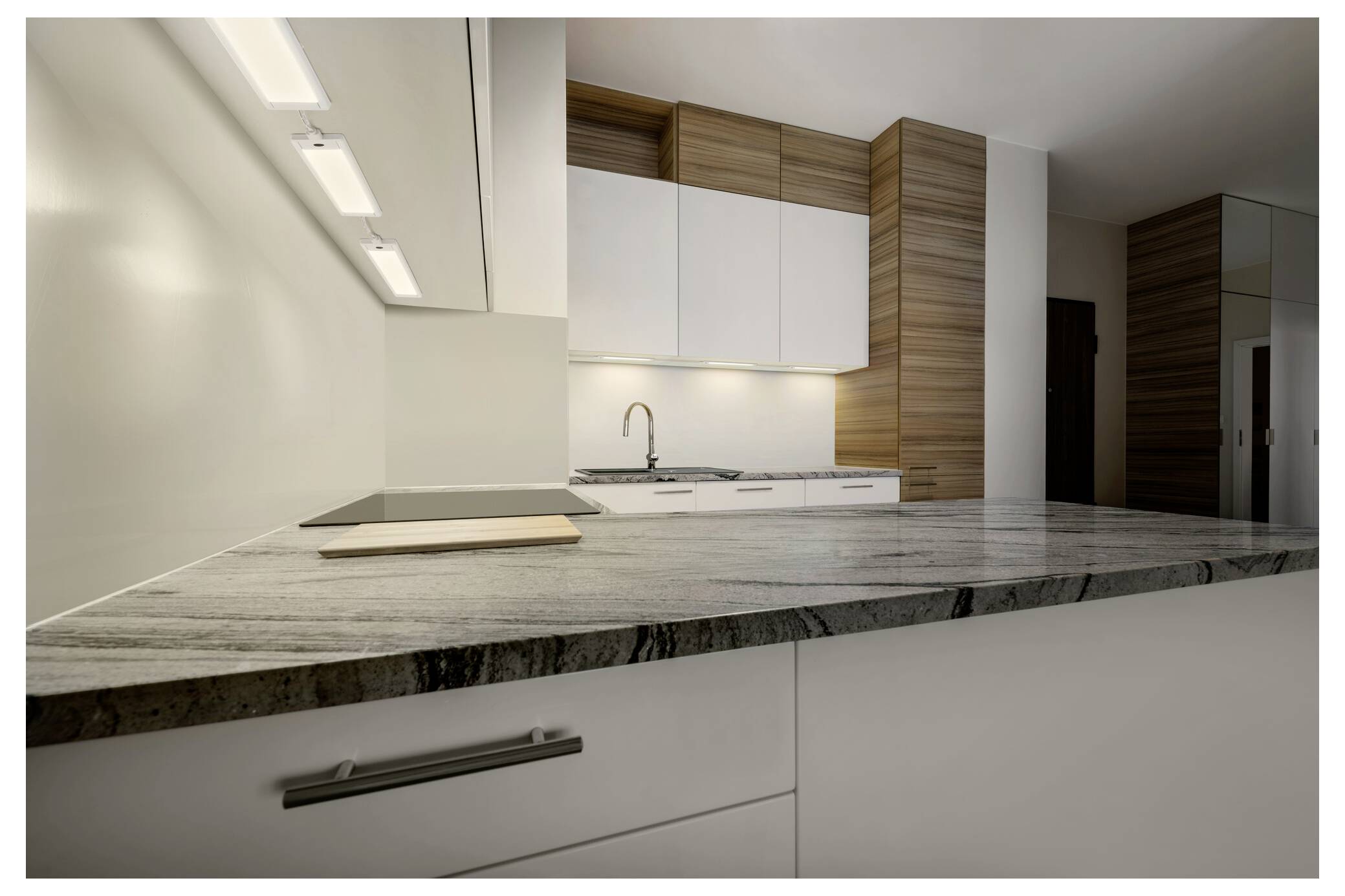 Modern keukeninterieur met witte kasten, houtaccenten, ingebouwde gootsteen en een groot grijs marmeren werkblad op de voorgrond.