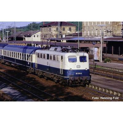 Blauw-en-crèmekleurige passagierstrein op een stationperron, met bovenleiding en perrongebouwen op de achtergrond.