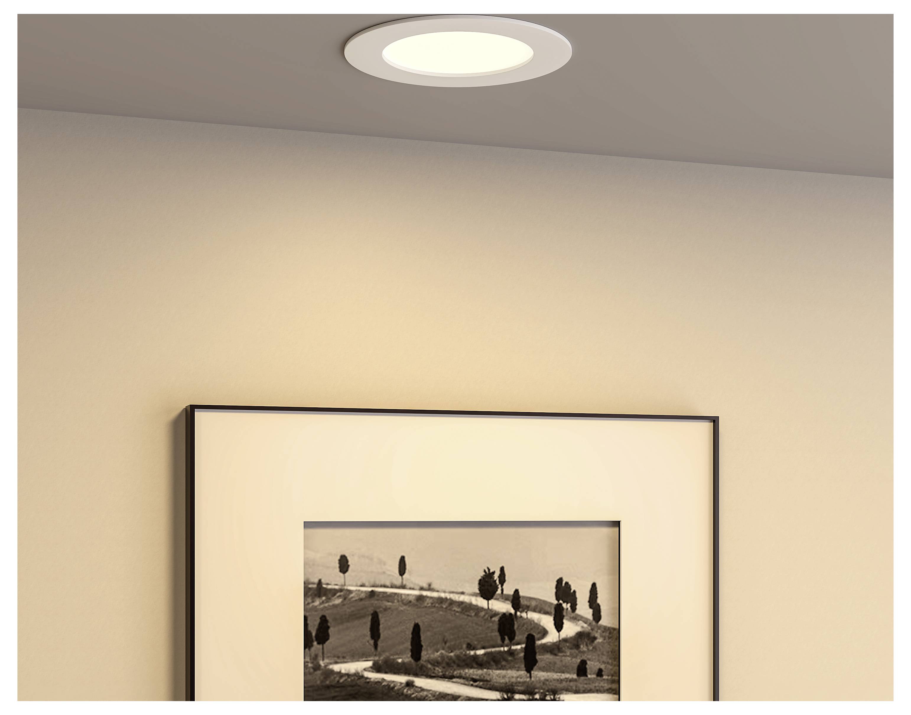 Ingelijste zwart-wit landschapsfoto opgehangen aan een beige muur onder een inbouwplafondlamp.