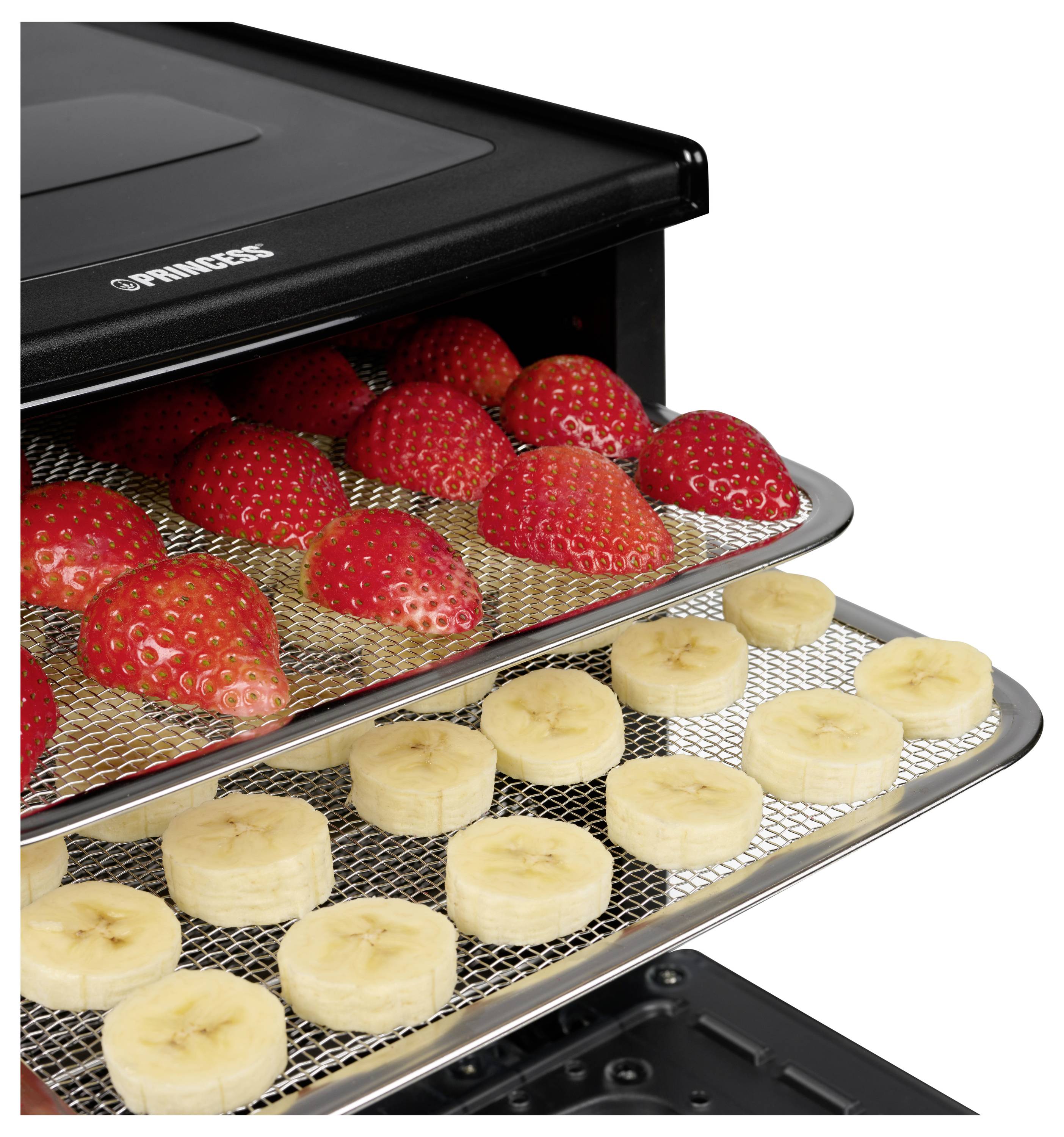 Voedseldroogoven met bakken aardbeien en bananenschijven die aan het drogen zijn in een zwart apparaat.