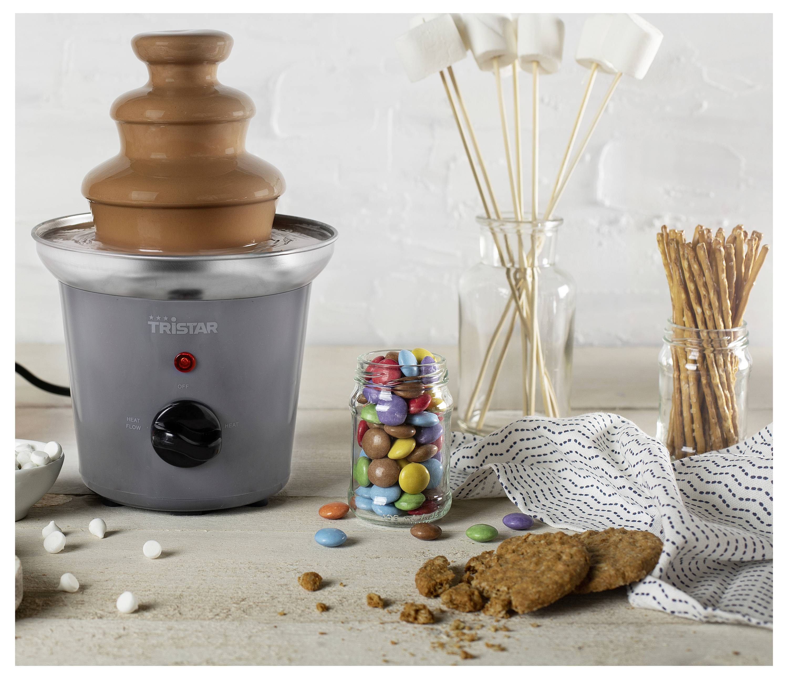 Chocoladefontein op een aanrecht van de keuken met snoep, koekjes, krakeling en prikkers die klaar zijn voor het onderdompelen.