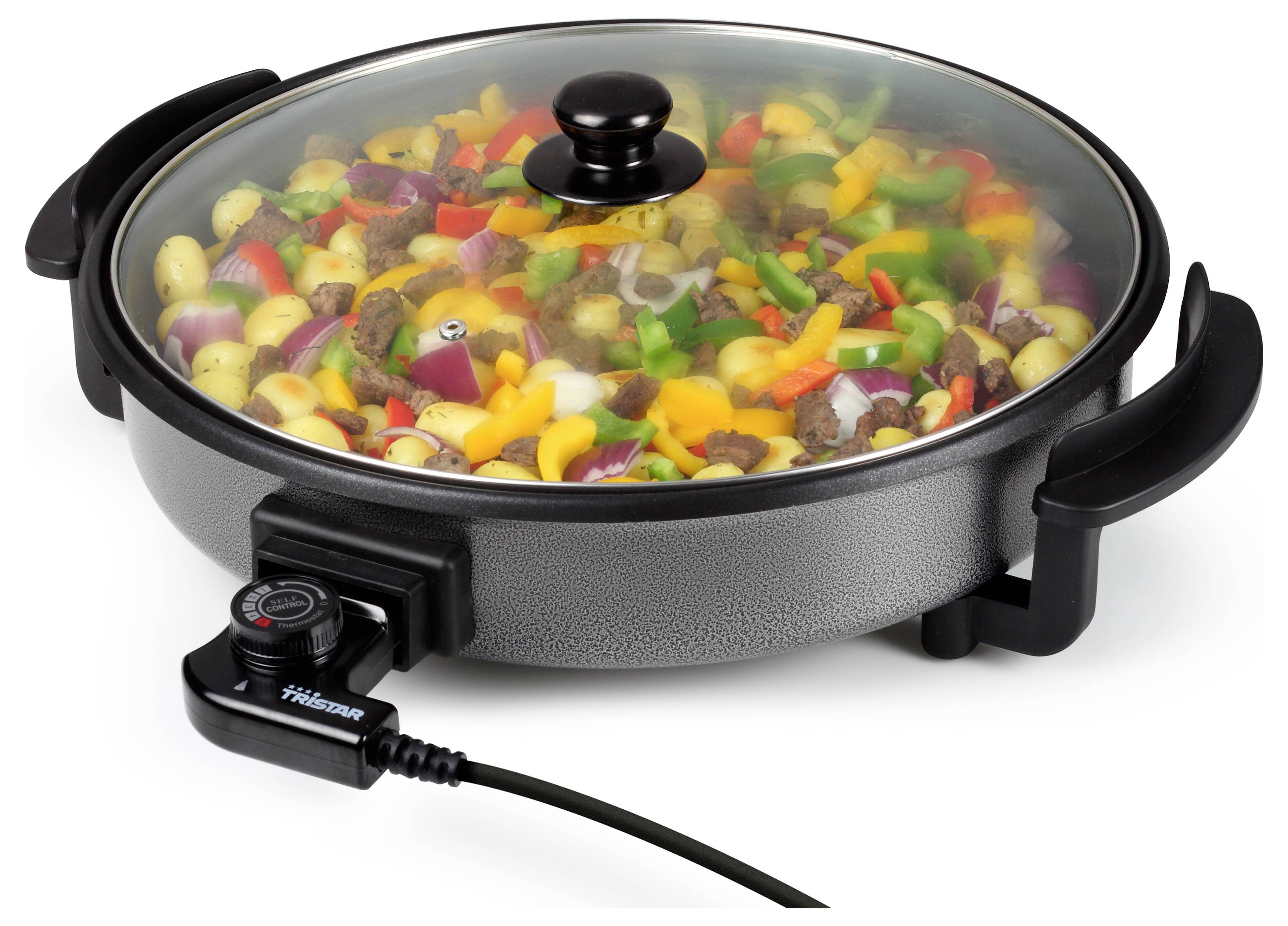 Elektrische koekepan met glazen deksel, gevuld met gemengde groenten en vlees, weergegeven aangesloten en aan het koken.
