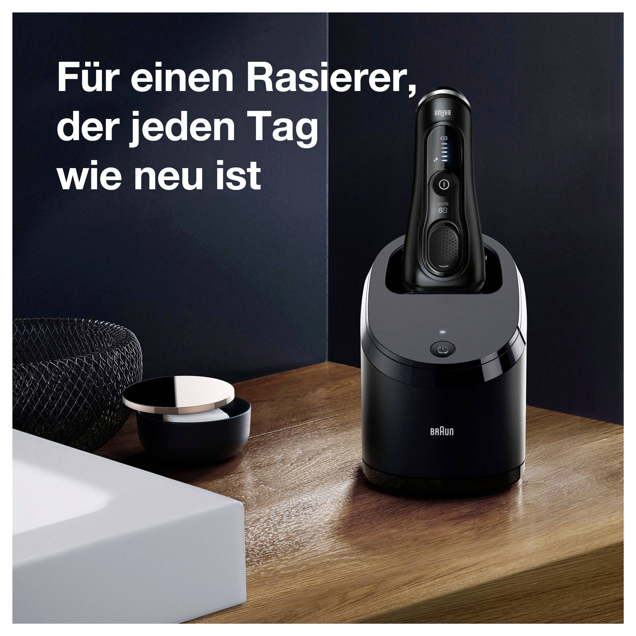Braun elektrisch scheerapparaat in een laad-/reinigingsdock op een houten oppervlak, met Duitse tekst: 'Voor een scheerapparaat dat elke dag als nieuw aanvoelt' (Voor een scheerapparaat dat elke dag als nieuw voelt).