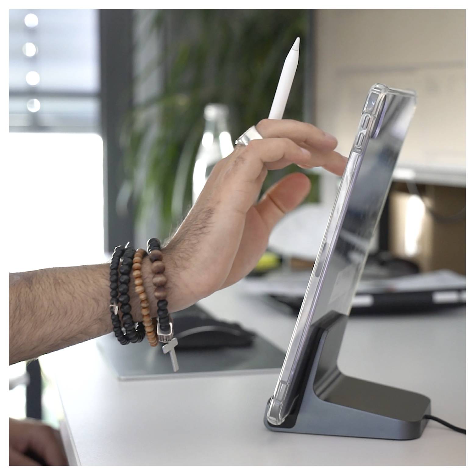 Hand die een stylus op een tablet in een desktopstandaard op een bureau gebruikt.