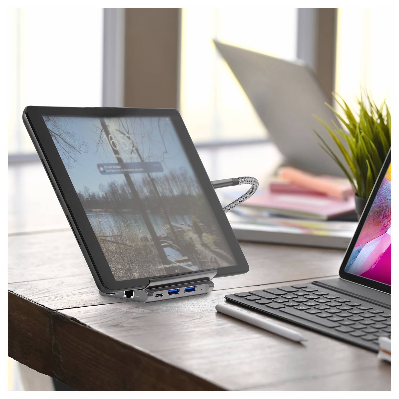 Tablet op een bureau verbonden met een laptop via een dockingstation, met een gespiegeld scherm in een helder huiskantoor.