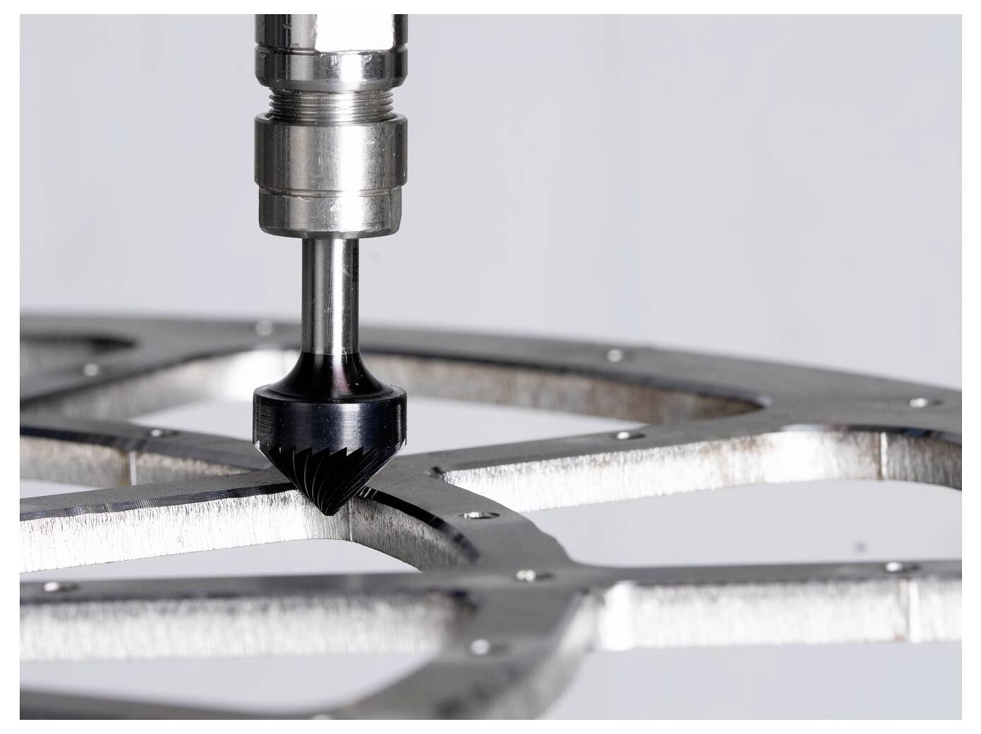 Close-up van een CNC freestool die een metalen onderdeel bewerkt, waarbij een gebogen sleuf in een bewerkt werkstuk wordt gevormd.
