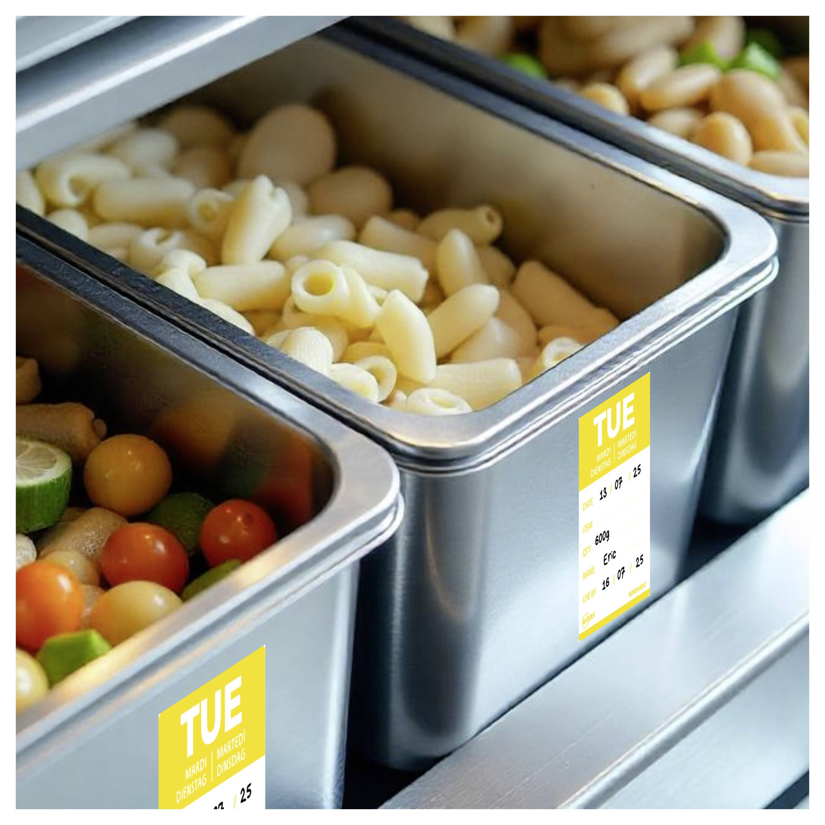 Buffet-stijl metalen dienbladen met pasta en groenten, elk met een geel 'DIN'-label, gerangschikt in een serveerbalie.