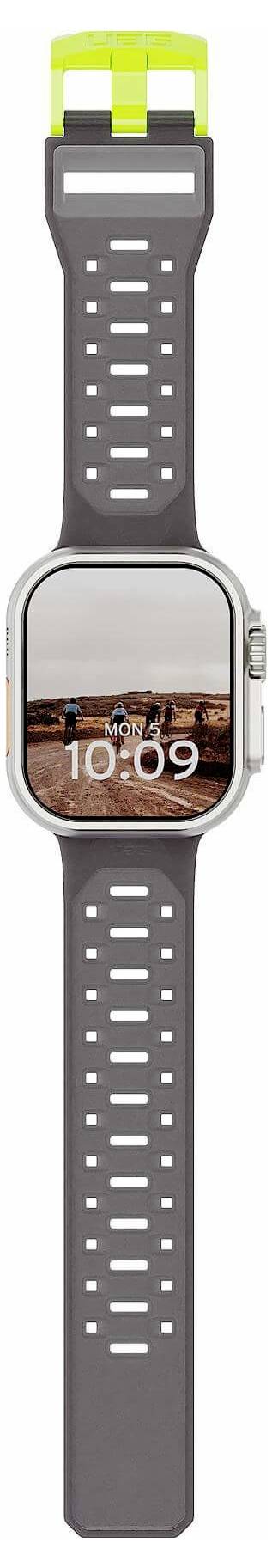 Smartwatch met grijze geperforeerde sportband en vierkant display dat 10:09 weergeeft boven een stadslandschapsfoto.