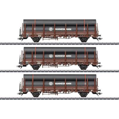 Drie zijdelingse goederentreinen met zwarte cilindrische ladingen op open wagens, gelabeld 'HANNESMANN', weergegeven in drie horizontale rijen gestapeld.