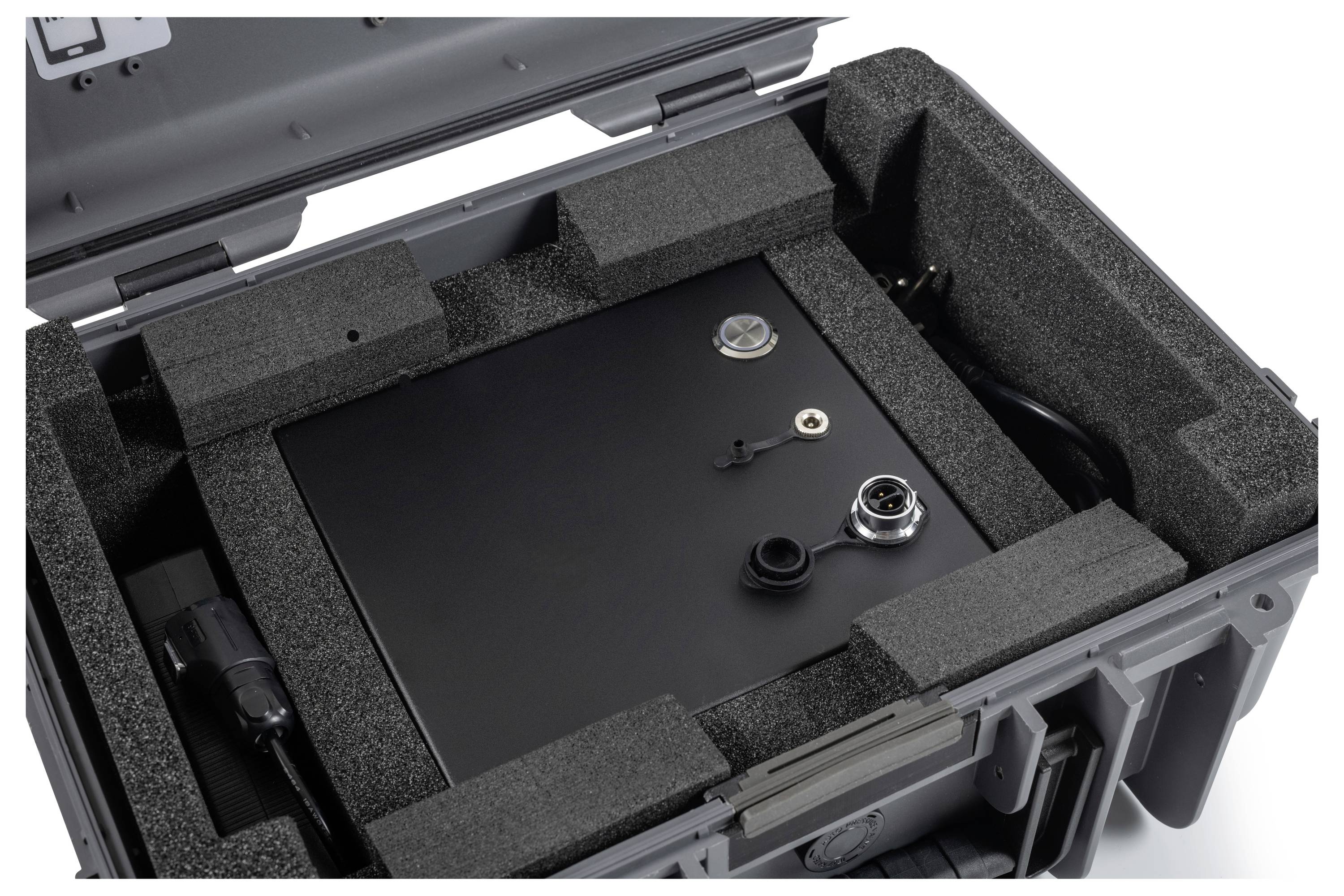 Open hard case met schuimkussen met daarin een zwart metalen apparaatenkast en aansluitonderdelen.