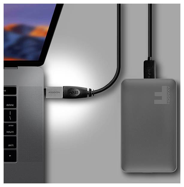 Laptop verbonden via USB-C-kabel met een grijze externe schijf of dockingstation met het label 'AXAGON' op een bureau