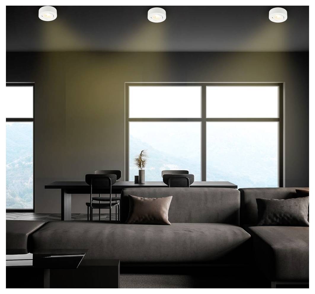 Moderne woonkamer met een donkerblauwe hoeksectional sofa die naar grote ramen kijkt, een eettafel erachter, en helder natuurlijk licht dat de minimalistische ruimte vult.