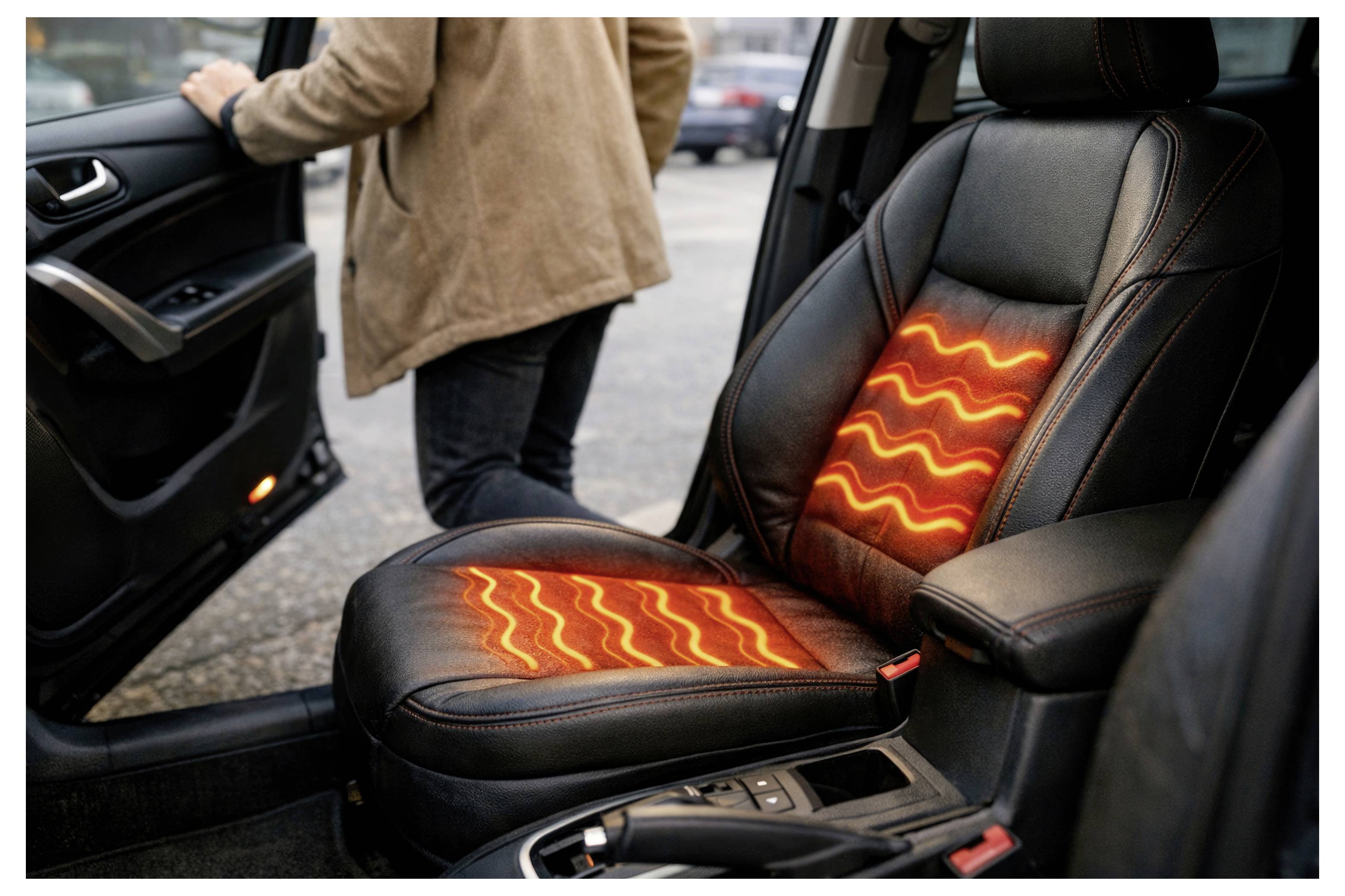 Auto-interieur met verwarmde bestuurdersstoel die oranje gloeit in het kussen en de rugleuning, terwijl een persoon buiten de open deur staat.