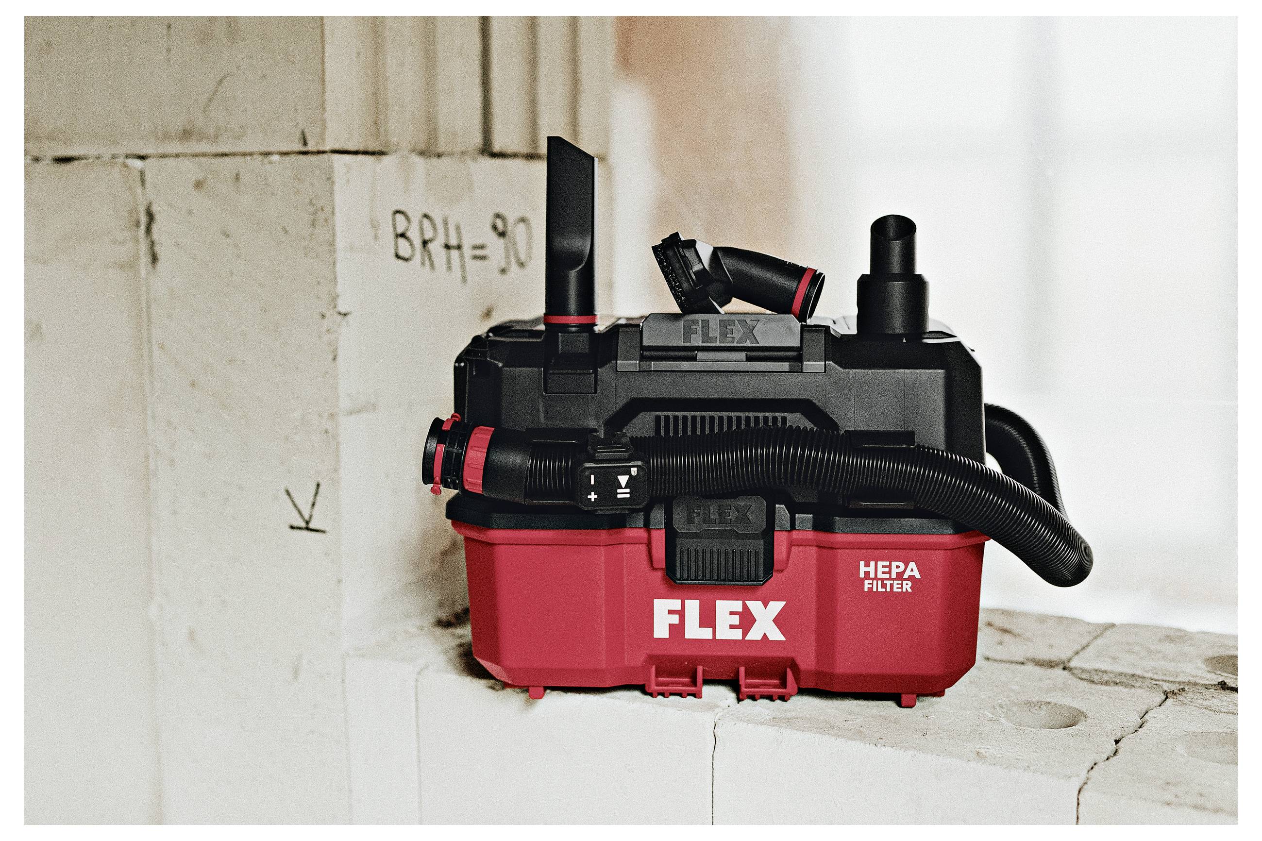 Rode FLEX stofzuiger met HEPA-filter op een stoffige constructiebermleiding naast een muur gemarkeerd met 'BRH=90'.