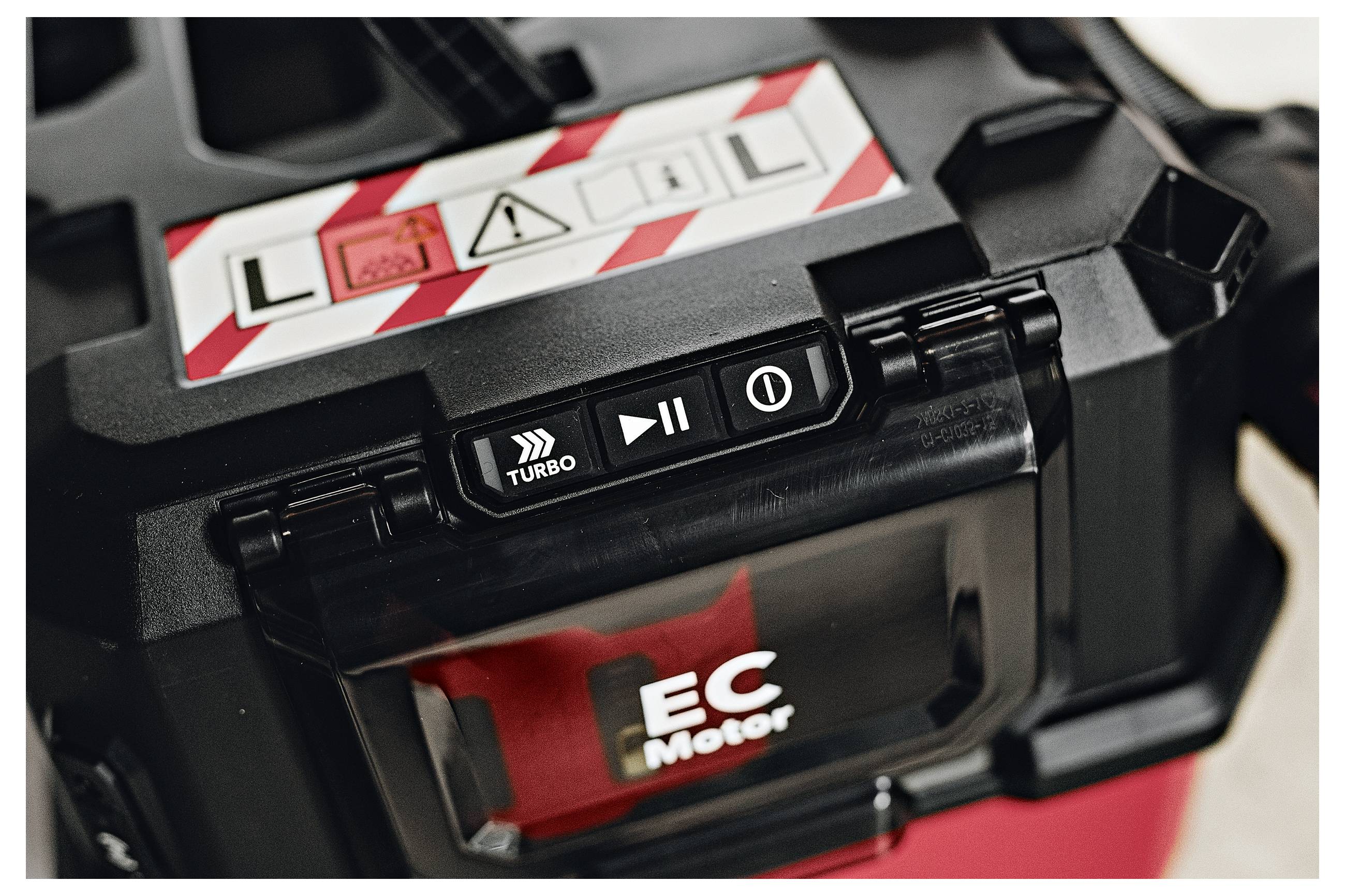 Close-up van een speelgoedautobatterijvak met een verwijderbare 'EC Motor'-pack en zichtbare turbo-, speel- en aan/uit-knoppen.
