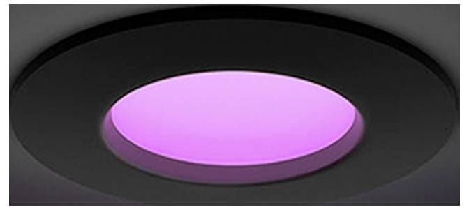 Close-up van een zwarte ingebouwde plafondlamp met een gloeiend roze-paars centrum.