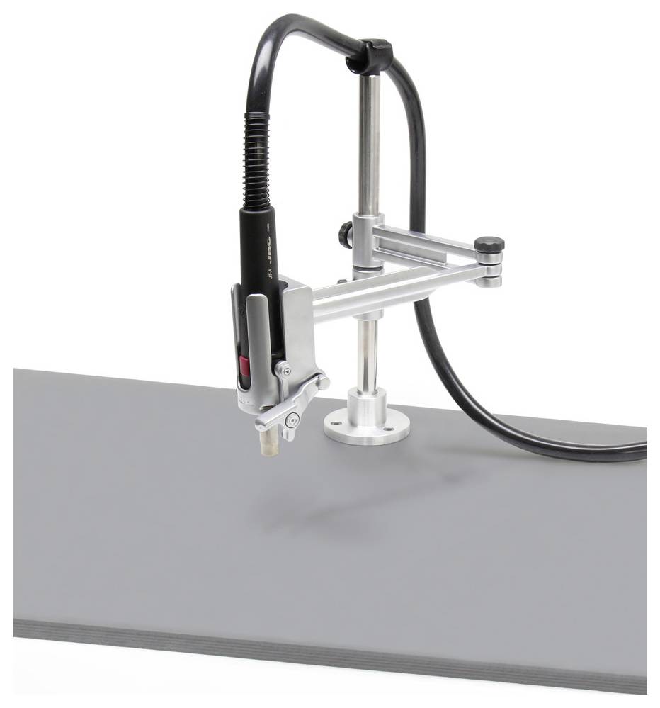 Gemonteerd handheld gereedschap met veerarm en slang gepositioneerd boven een grijze werkoppervlak, waarschijnlijk een robotisch of pneumatisch snijapparaat.