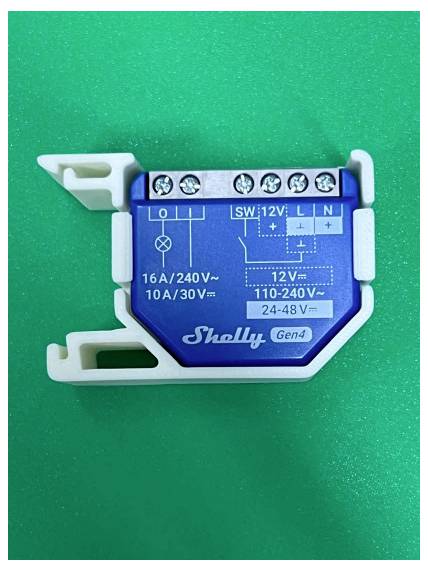 Blue Shelly Gen4 relaismodule op een groene achtergrond, met schroefklemmen en gedrukte bedrading labels voor 12V en 110-240V.