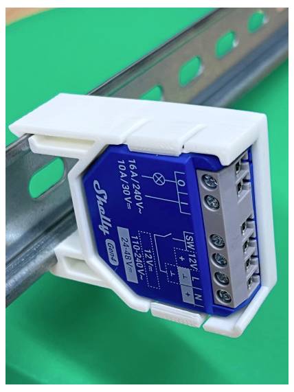 Close-up van een op DIN-rail gemonteerde elektrische relaismodule met gelabelde aansluitklemmen, blauwe frontplaat en wit kunststofhuis.
