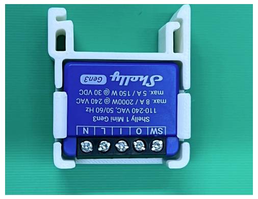 Blue Shelly 1 Mini Gen3 slimme relaismodule met schroefklemmen, getoond op een groene achtergrond; label vermeldt 110-240V AC en max 5A/2400W.