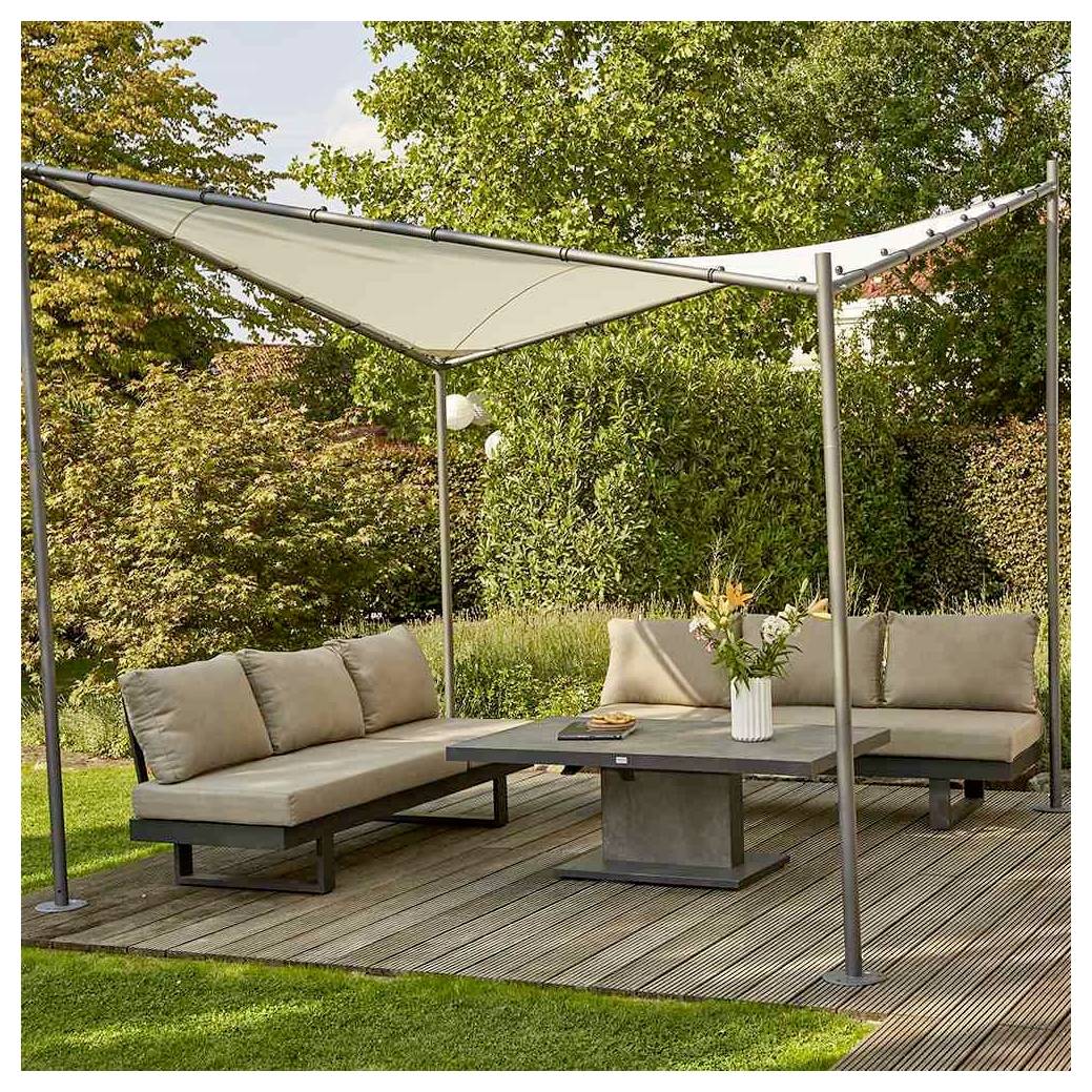 Modern buitenzithoek met twee beige hoeksectionals, laag tafelblad en luifel op een houten terras in een tuin.