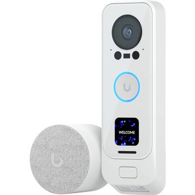 Witte slimme deurbel camera met een groot objectief, gloeieende ringknop, klein display met de tekst 'WELKOM' en een bijpassend rond luidspreker-/accessoire ernaast.