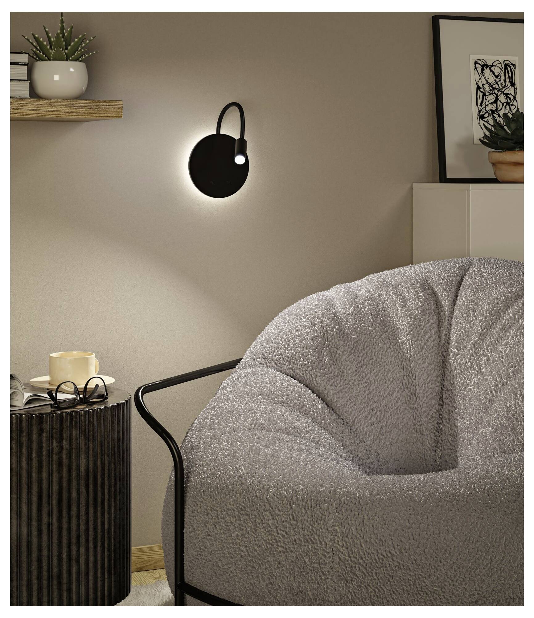 Gezellig woonkamer hoekje met een zwart wandlampje, comfortabele grijze stoel, bijzettafel en kleine decoratieve planken en planten.