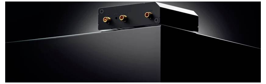 Zwart rechthoekig elektronisch apparaat met drie verlichte aansluitingen bovenop, getoond in een donkere productfoto-stijl close-up.