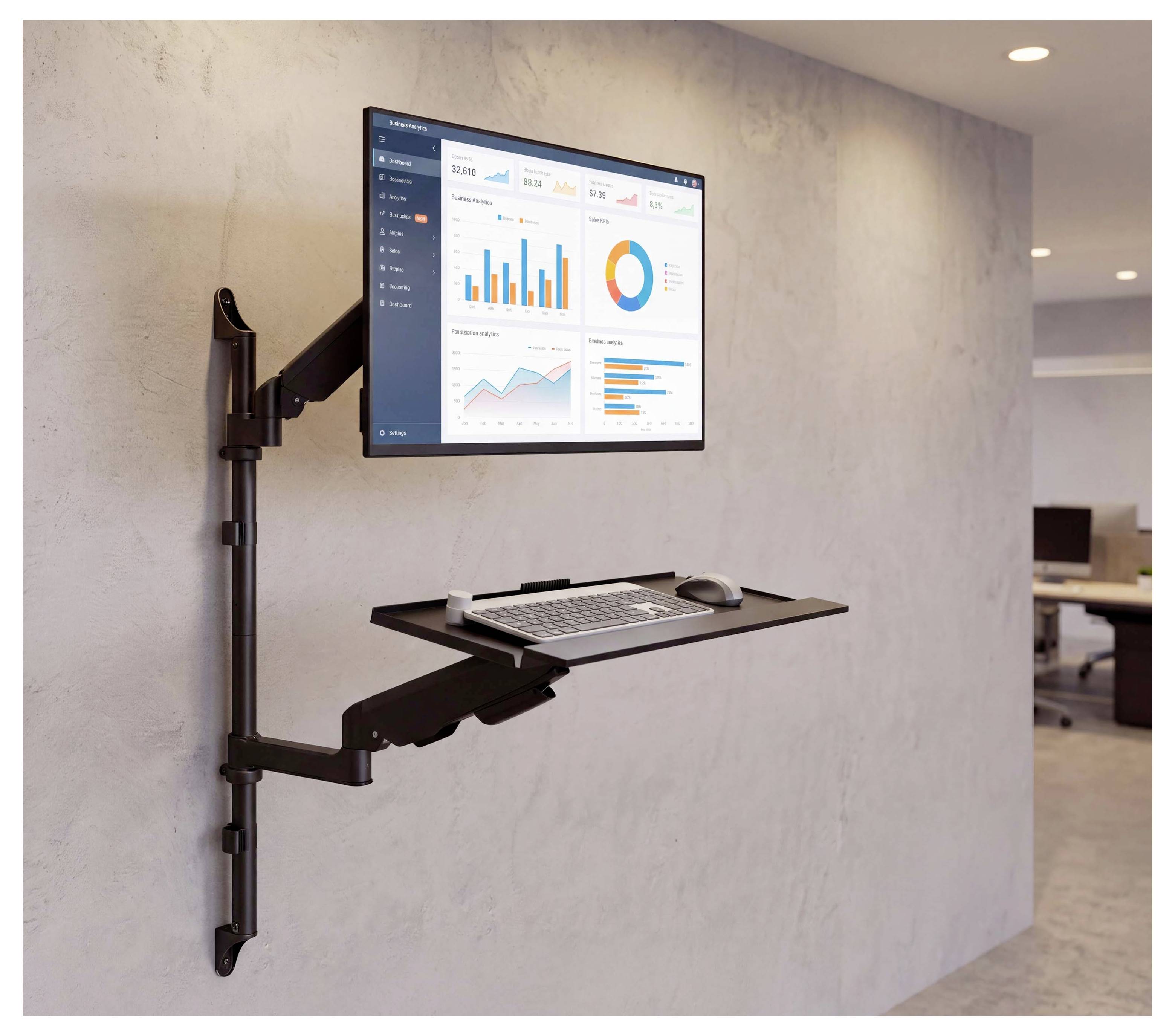 Aan de muur gemonteerd verstelbaar werkstation met een monitor die dashboardgrafieken toont, een toetsenbordlade en een muis in een kantooromgeving.