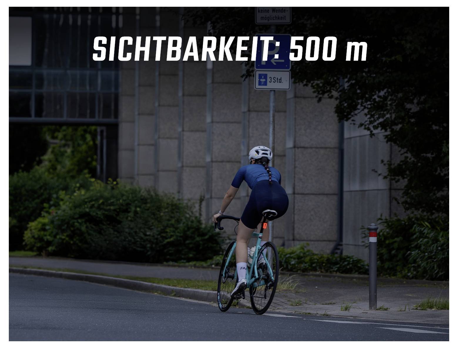 Wielrenster in donkere straat; overlay 'ZICHTBAARHEID: 500 m' waarschuwt voor slechte zichtbaarheid.