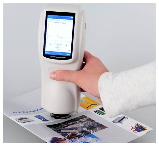 Een hand houdt een draagbare spectrofotometer over een afgedrukt kleurentestblad om kleuren te meten.