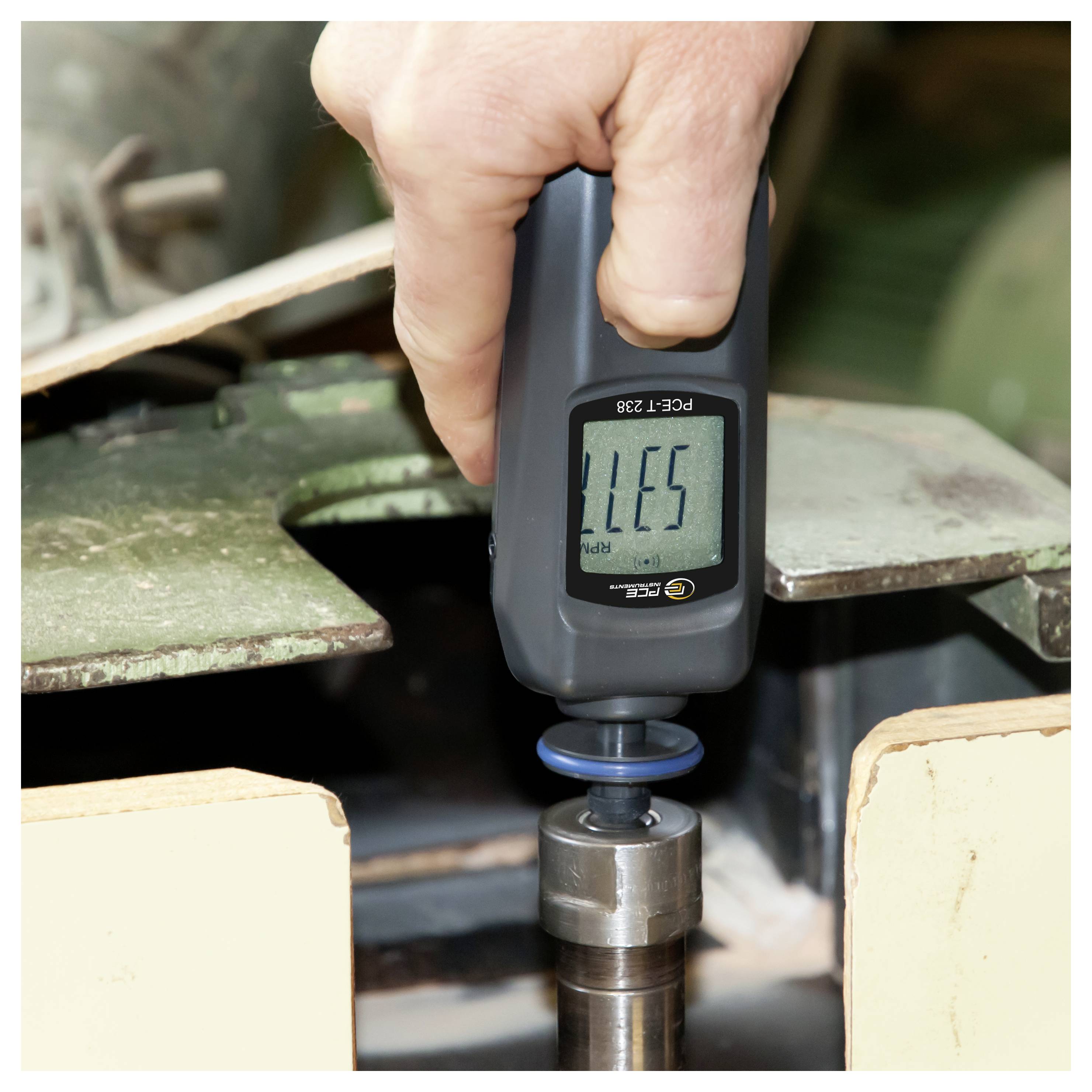 Handheld digitale meter die een metalen spil of as in een machineopstel meet.