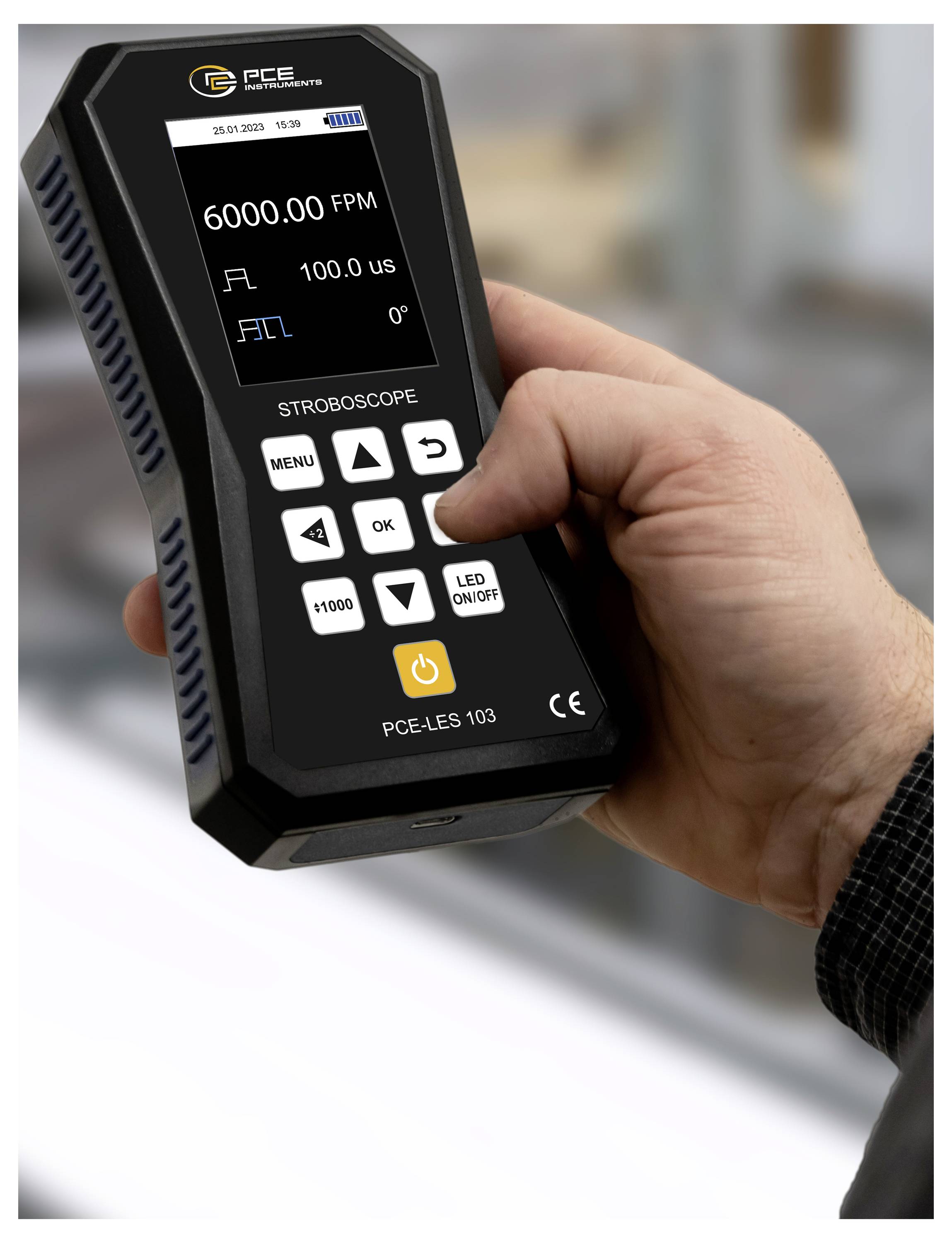 Hand die een PCE handheld stroboscoop vasthoudt met 6000.00 FPM, 100.0 us en 0° op het display.