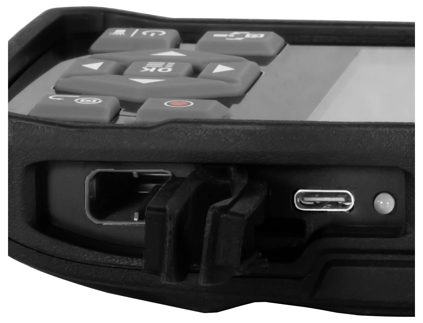 Close-up van een robuust elektronisch apparaat met bedieningsknoppen bovenop en een USB-C oplaadpoort met een aangesloten connector.