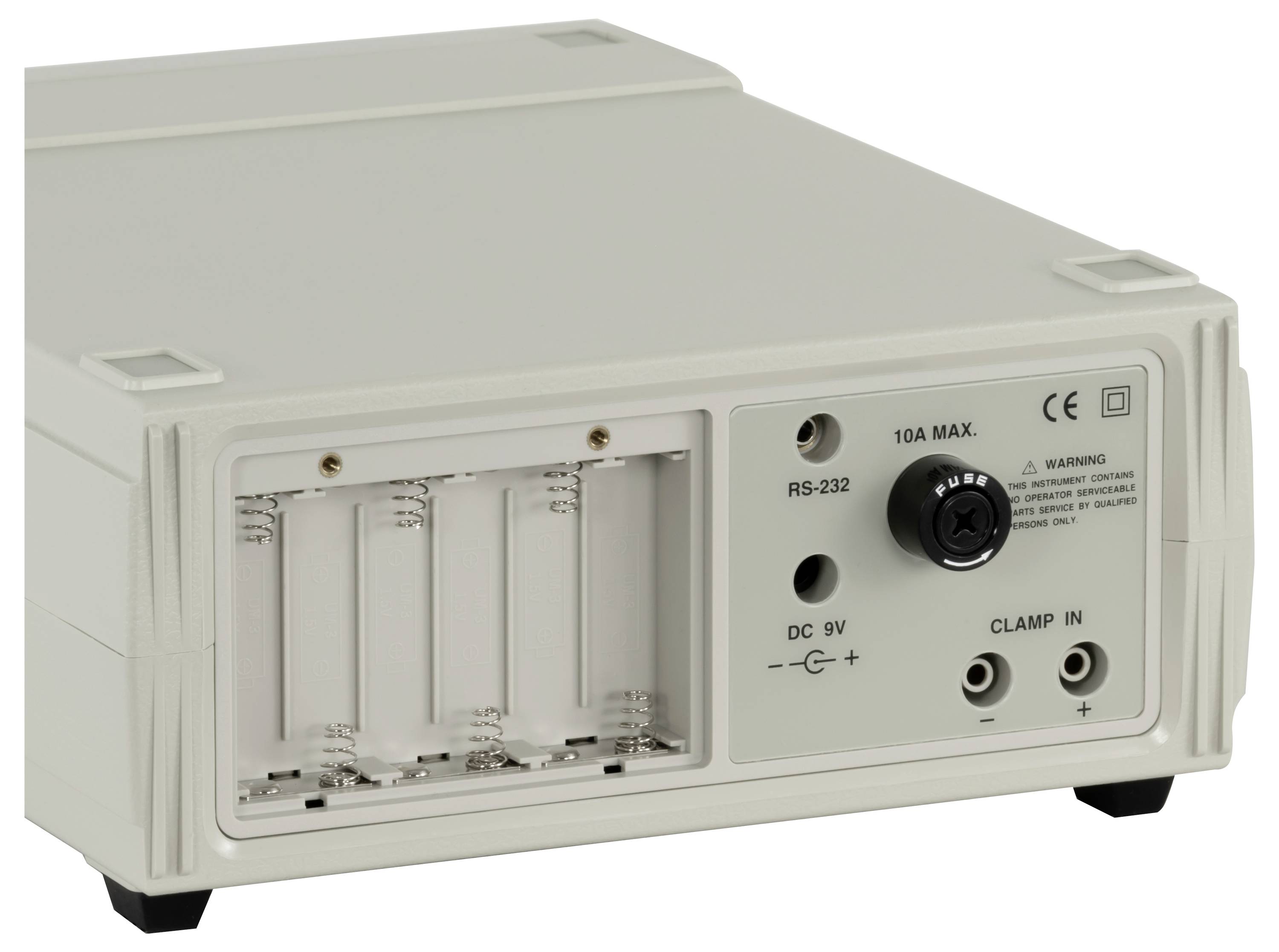Achterkant van een beige elektronisch apparaat met een 4-batterij compartiment, RS-232 poort, DC 9V ingang en klemterminals.