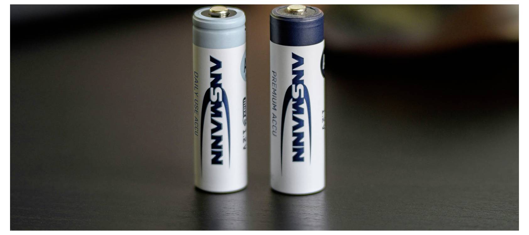 Twee Ansmann AA-batterijen rechtop op een donker oppervlak.