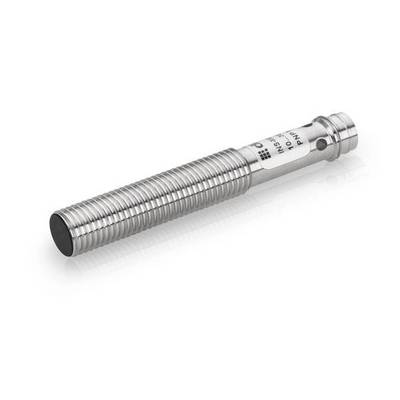 Een cilindrische gemetalliseerde nabijheidssensor met een draad en een zwart voelend uiteinde en een gelabelde aansluitingskant op een witte achtergrond.