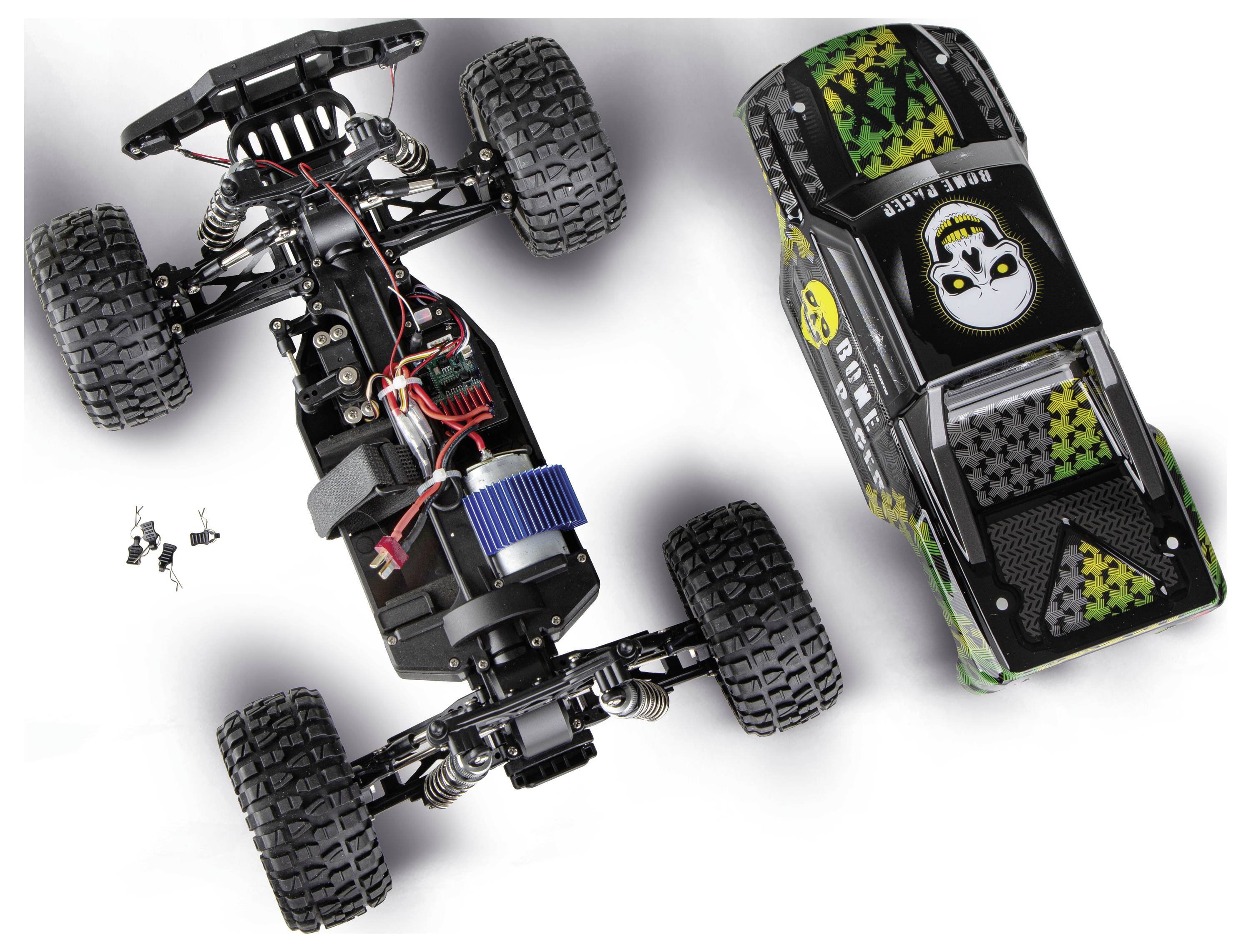 Bovenaanzicht van een RC terreinwagen chassis naast zijn versierde carrosserieschaal, met zichtbare motor, bedrading, ophanging en vier grote nobbelige banden.