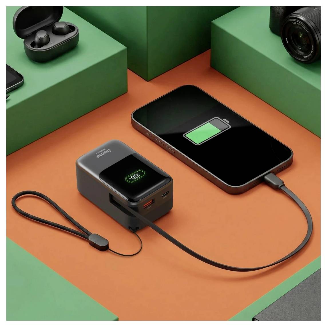 Smartphone die naast een compacte powerbank op een oranje oppervlak wordt opgeladen, met een groen batterijpictogram op het telefoonscherm.