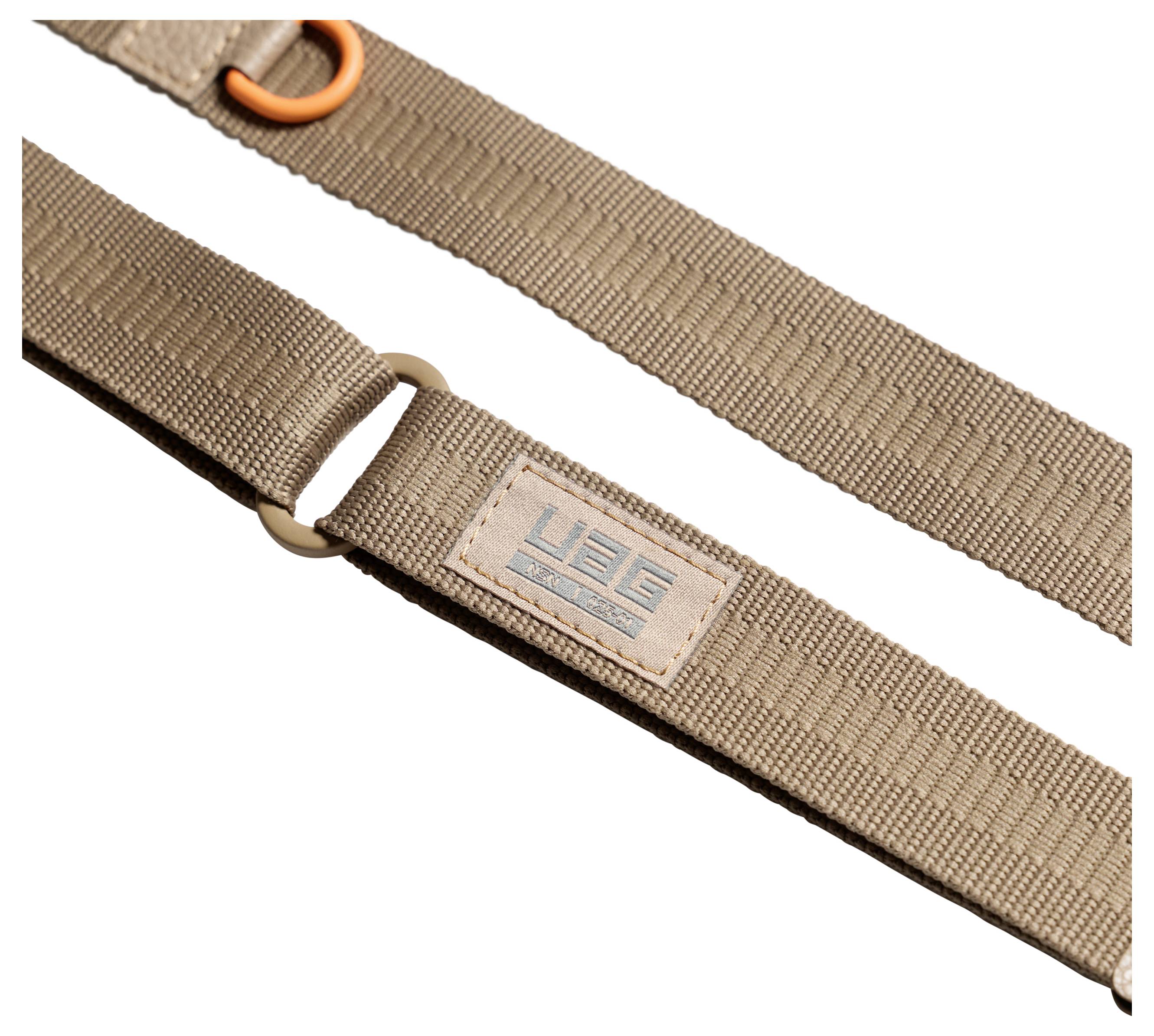 Beige nylon riem met metalen ring en gestitchte 'UGG' logo patch op een witte achtergrond.